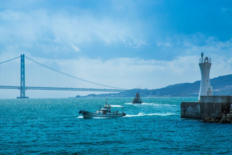 明石海峡大橋が見える海で船が進んでいる